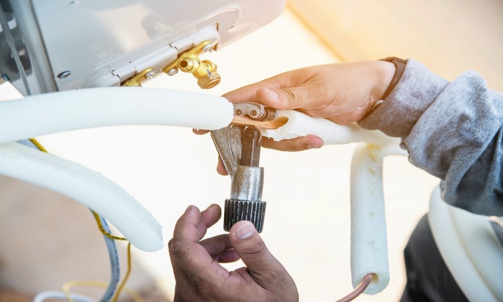 Man is installing wall compressor of air conditioner during hot season